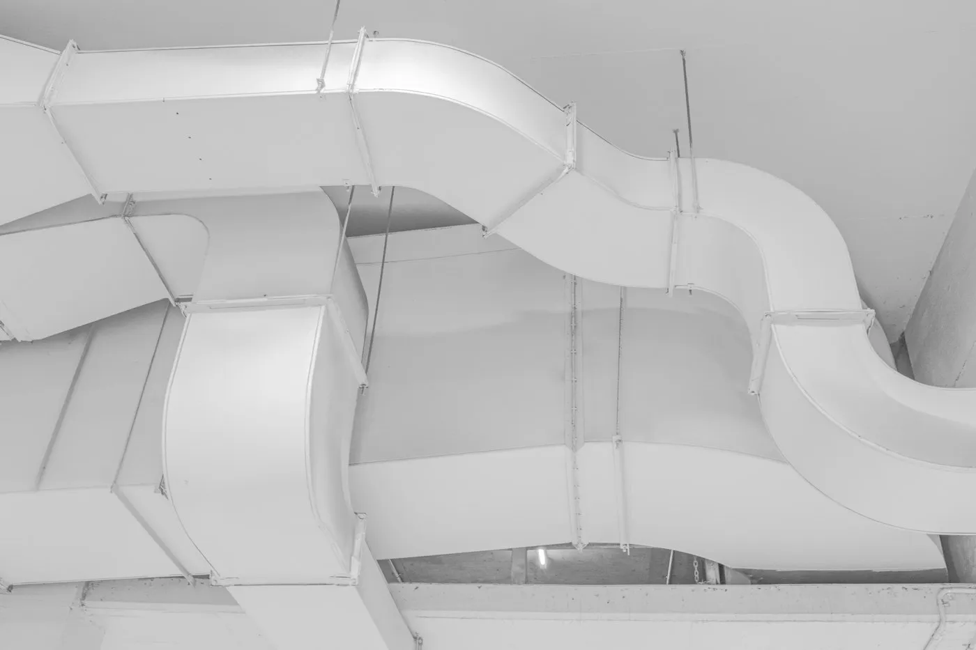 White ventilation ducts running under a concrete ceiling