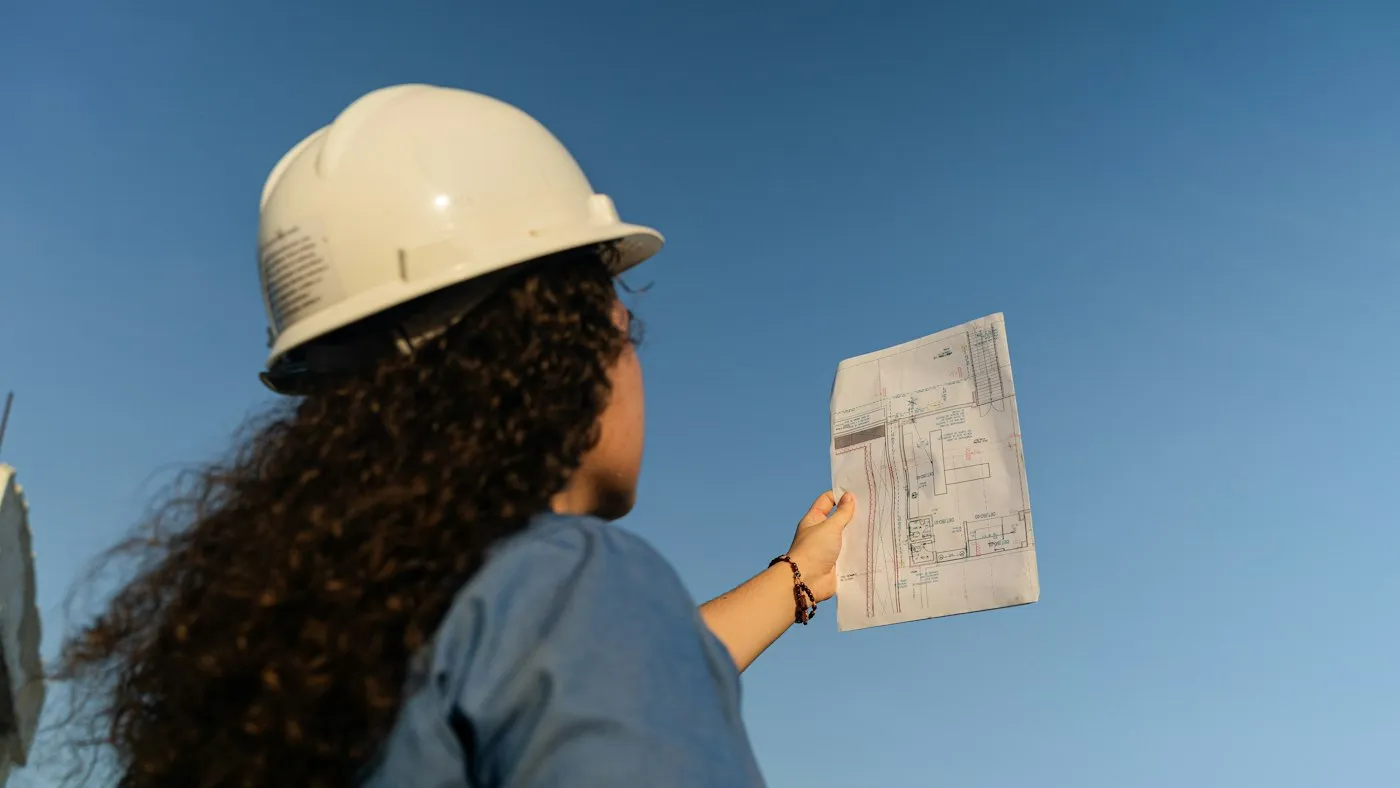An engineer in a hard hat holding up a building plan